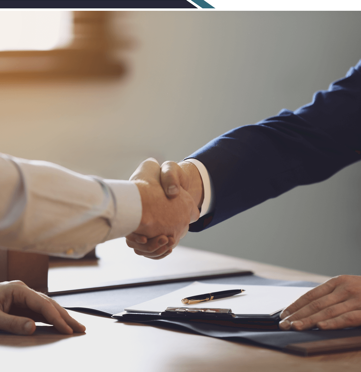 Handshake over a business desk with documents.